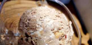 Κρεμώδες σπιτικό παγωτό μόκα σε ένα μπολ, πασπαλισμένο με θρυμματισμένα μπισκότα και φουντούκια.