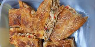 Μια χρυσαφένια, ψημένη πιπερόπιτα κομμένη σε κομμάτια, που φαίνεται η λαχταριστή γέμιση με τα χρωματιστά λαχανικά και το τυρί.