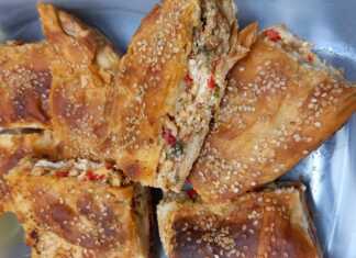 Πιπερόπιτα με άρωμα καλοκαιριού Μια χρυσαφένια, ψημένη πιπερόπιτα κομμένη σε κομμάτια, που φαίνεται η λαχταριστή γέμιση με τα χρωματιστά λαχανικά και το τυρί.