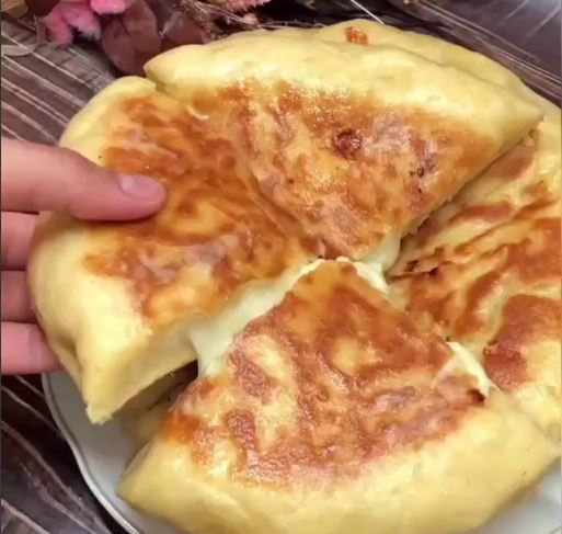 Pites me tiri Τρεις χρυσαφένιες στρογγυλές πιτούλες με λιωμένο τυρί σε ένα πιάτο.