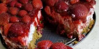 Ένα λαχταριστό τσιζκέικ φράουλα στολισμένο με φρέσκες κομμένες φράουλες.