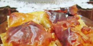 Φρέσκο, χρυσαφένιο σπιτικό γαλακτομπούρεκο κομμένο σε τετράγωνα κομμάτια, με το σιρόπι να γυαλίζει στην επιφάνεια.