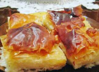 Φρέσκο, χρυσαφένιο σπιτικό γαλακτομπούρεκο κομμένο σε τετράγωνα κομμάτια, με το σιρόπι να γυαλίζει στην επιφάνεια.