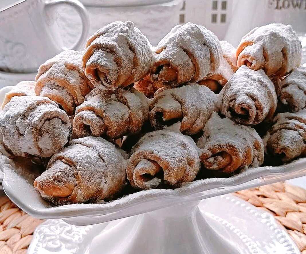 Φρεσκοψημένα κρουασανακια πασπαλισμένα με άχνη ζάχαρη σε ένα πιάτο