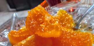 Γλυκό κουταλιού πορτοκάλι σε ένα γυάλινο μπολ, με κομμάτια πορτοκαλιού να γυαλίζουν στο σιρόπι.