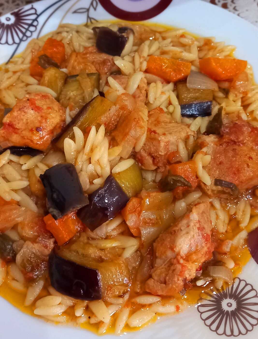 hoirino me melitzana Ένα πιάτο με χοιρινό κρέας, κριθαράκι και κομμάτια μελιτζάνας σε πλούσια σάλτσα.