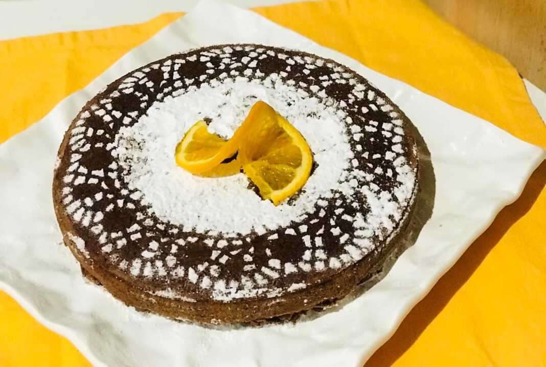 Μια στρογγυλή τορτα καπρέζε πασπαλισμένη με άχνη ζάχαρη.