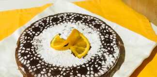 Μια στρογγυλή τορτα καπρέζε πασπαλισμένη με άχνη ζάχαρη.