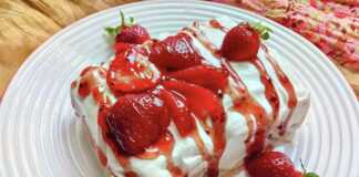 Γλυκό με στρώσεις από ζουμερές φράουλες και λευκή, αφράτη σαντιγί γιαουρτιού σε ένα γυάλινο μπολ.