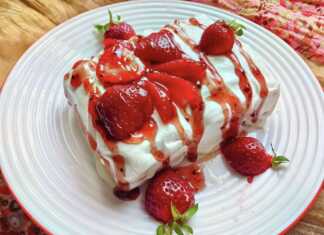 Γλυκό με στρώσεις από ζουμερές φράουλες και λευκή, αφράτη σαντιγί γιαουρτιού σε ένα γυάλινο μπολ.