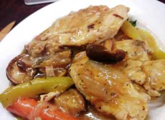 Μαγειρεμένο στήθος κοτόπουλου λεμονάτο σε κατσαρόλα, γαρνιρισμένο με φέτες λεμονιού και φρέσκα μυρωδικά.