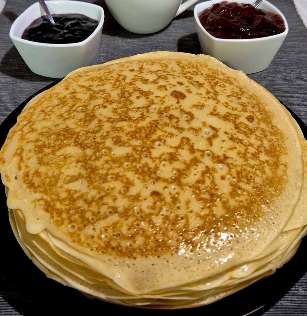 Σωρός από χρυσαφένιες κρέπες αλειμμένες με βούτυρο, έτοιμες για σερβίρισμα με μαρμελάδα.