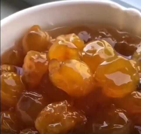 Ένα γυάλινο μπολ γεμάτο με λαμπερά, κεχριμπαρένια λευκά κεράσια σε παχύρρευστο σιρόπι.