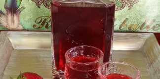 Ένα μπουκάλι γεμάτο με κόκκινο σπιτικό λικέρ φράουλας.