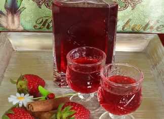 Ένα μπουκάλι γεμάτο με κόκκινο σπιτικό λικέρ φράουλας.