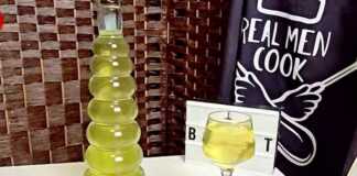 Δύο γυάλινα μπουκάλια γεμάτα με κίτρινο λικέρ λεμονιού, δίπλα σε λεμόνια και φλούδες λεμονιού.