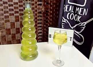 Δύο γυάλινα μπουκάλια γεμάτα με κίτρινο λικέρ λεμονιού, δίπλα σε λεμόνια και φλούδες λεμονιού.