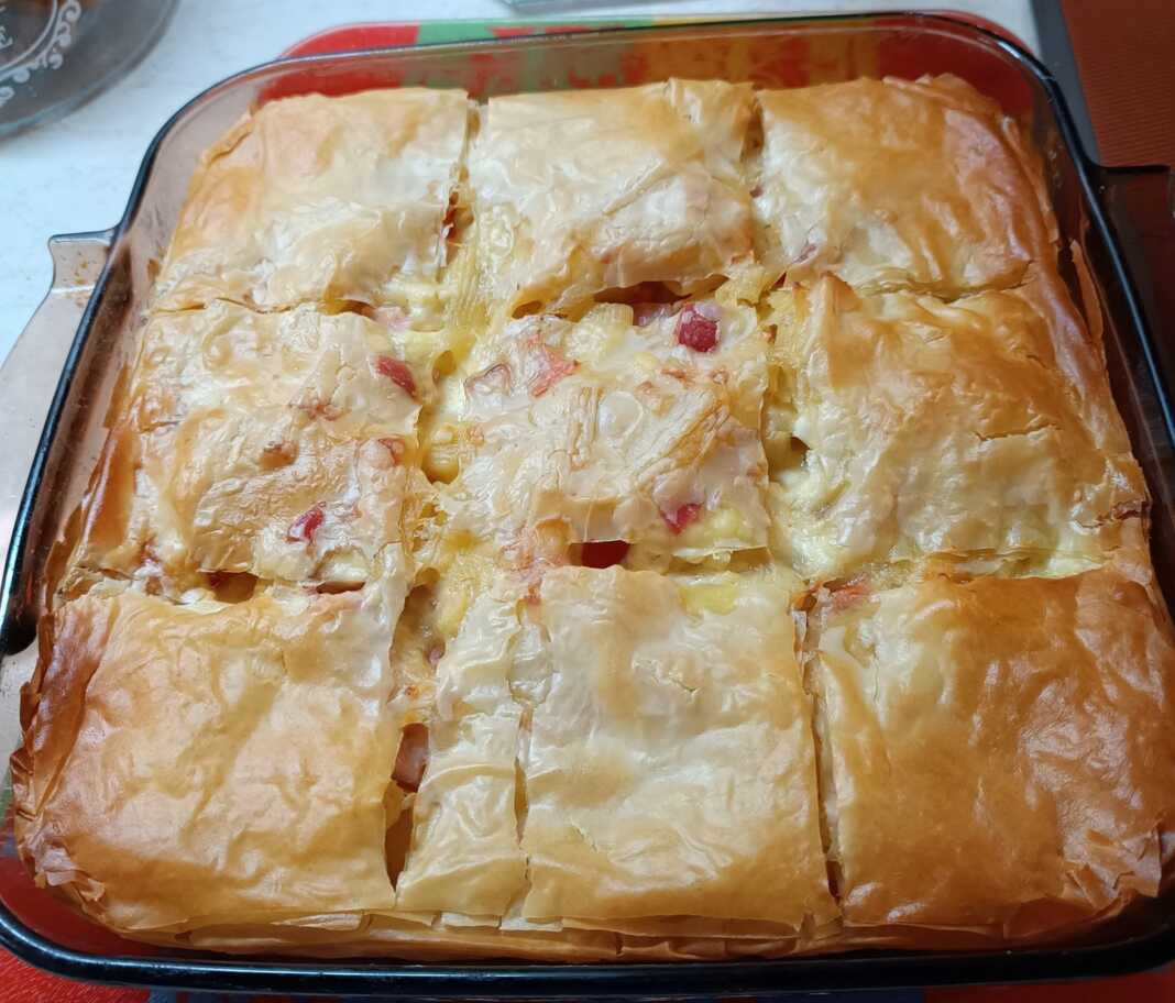 Ένα ταψί με χρυσαφένια, κομμένη σε μερίδες μακαρονόπιτα με φύλλο κρούστας.