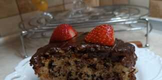 Ένα κομμάτι μυρμήγκατο σε πιατέλα, ένα κέικ σιροπιασμένο με γλάσο σοκολάτας και φρέσκιες φράουλες στην κορυφή.