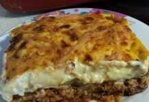 Ένα κομμάτι μουσακά με στρώσεις από πατάτες, μελιτζάνες, κιμά και μια χρυσαφένια κρούστα μπεσαμέλ σε ένα πιάτο.