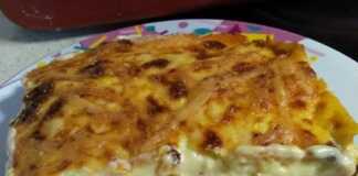 Ένα κομμάτι μουσακά με στρώσεις από πατάτες, μελιτζάνες, κιμά και μια χρυσαφένια κρούστα μπεσαμέλ σε ένα πιάτο.