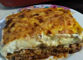 Ένα κομμάτι μουσακά με στρώσεις από πατάτες, μελιτζάνες, κιμά και μια χρυσαφένια κρούστα μπεσαμέλ σε ένα πιάτο.