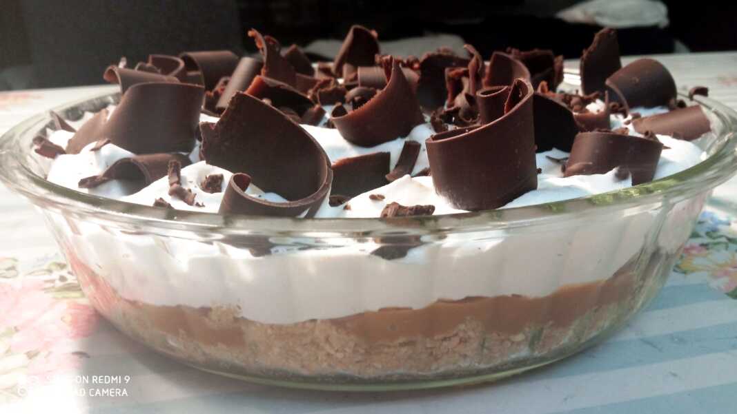 Ένα γλυκό μπανόφι σε ένα γυάλινο ταψί, με στρώσεις από θρυμματισμένα μπισκότα, καραμέλα, φέτες μπανάνας, σαντιγί και τριμμένη σοκολάτα.