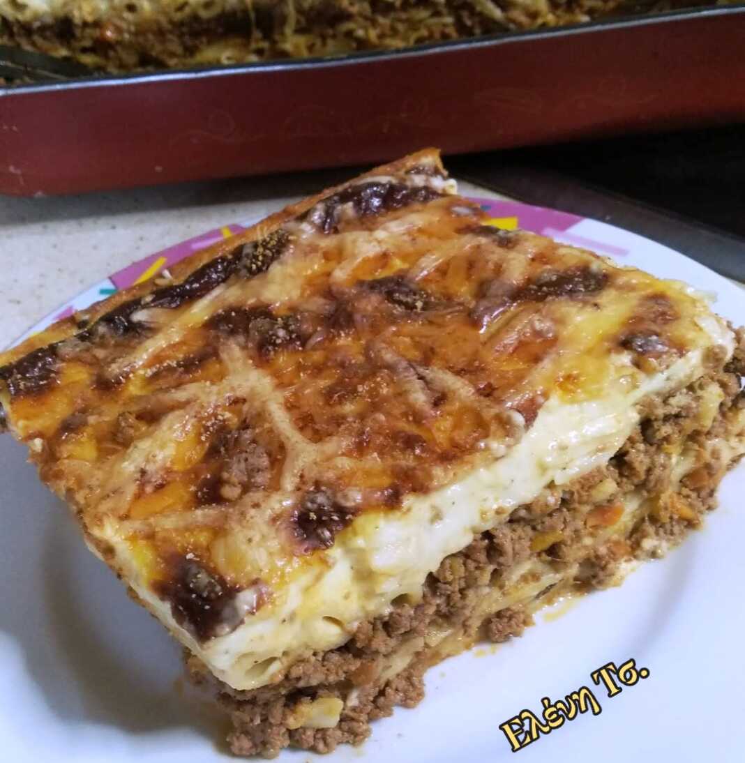 Ένα λαχταριστό ταψί με παστιτσάρα, έτοιμο να σερβιριστεί, με χρυσαφένια κρούστα μπεσαμέλ και τριμμένο τυρί.