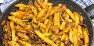 Ένα τηγάνι με χρυσαφένιες τηγανητές πατάτες ανακατεμένες με σωταρισμένα μανιτάρια και φέτες κρεμμυδιού.