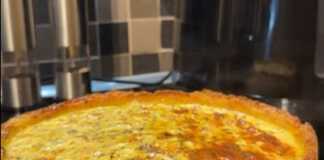 Μια στρογγυλή πατατόπιτα που μοιάζει με κέικ, με λαχανικά και τριμμένο τυρί στην επιφάνεια.