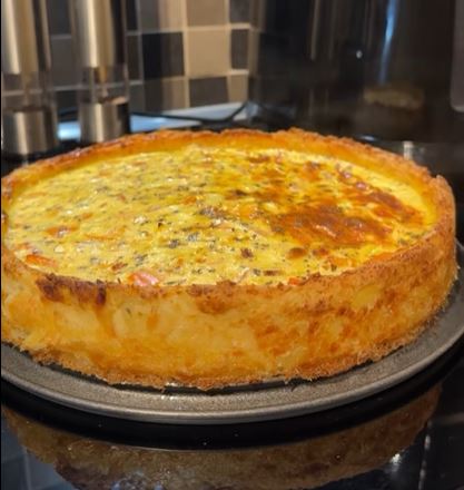 patatopita_fantastiki Μια στρογγυλή πατατόπιτα που μοιάζει με κέικ, με λαχανικά και τριμμένο τυρί στην επιφάνεια.