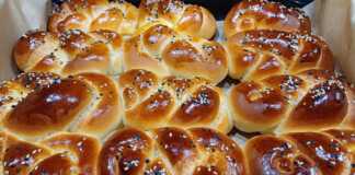 Ένα ταψί με χρυσαφένια μίνι ψωμάκια κομποι, αλειμμένα με αυγό και πασπαλισμένα με σουσάμι.