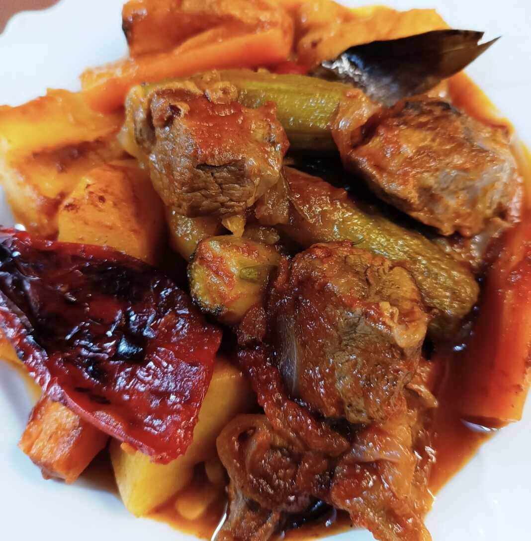 Ένα πιάτο με ζουμερό ραγού μοσχαριού και πολύχρωμα λαχανικά σε πλούσια σάλτσα.