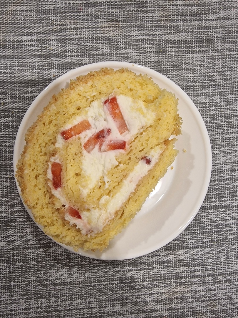 Φωτογραφία με ρολό παντεσπάνι γεμιστό με φράουλες και κρέμα γιαουρτιού.