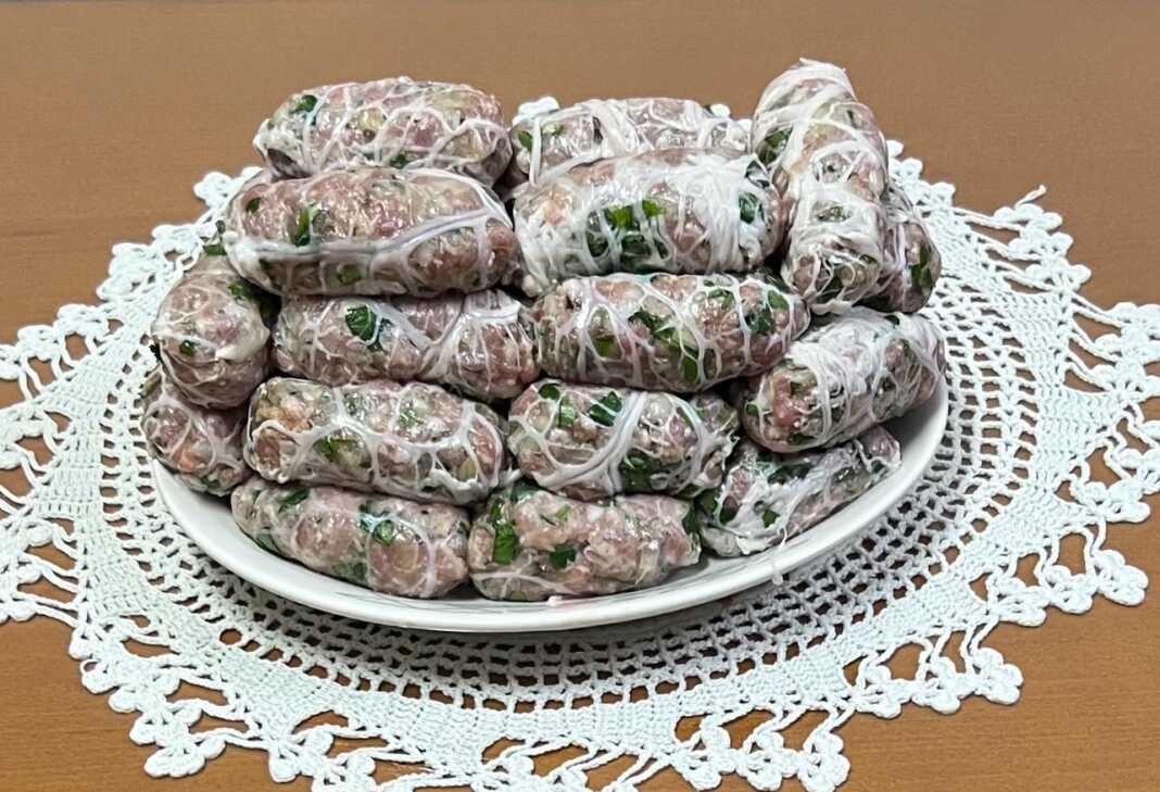 Ωμές σεφταλιές τυλιγμένες με την χαρακτηριστική λεπτή μεμβράνη (πάνα) έτοιμες για ψήσιμο.