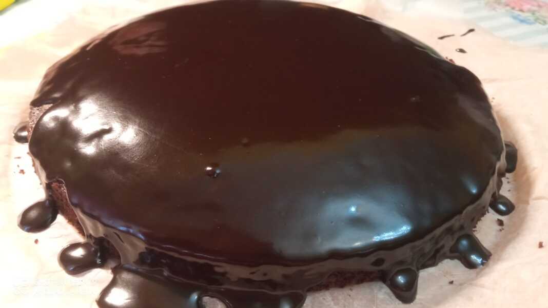 Μια λαχταριστή σοκολατόπιτα σε ένα ταψί, καλυμμένη με γυαλιστερό γλάσο σοκολάτας.