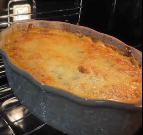 Ένα χρυσαφένιο σουφλέ κοτόπουλο με μανιτάρια σε ένα ταψί, πασπαλισμένο με λιωμένο τυρί.