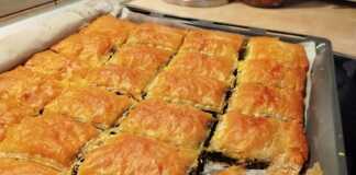 Μια χρυσαφένια σπανακοτυρόπιτα κομμένη σε μερίδες σε ένα ταψί.