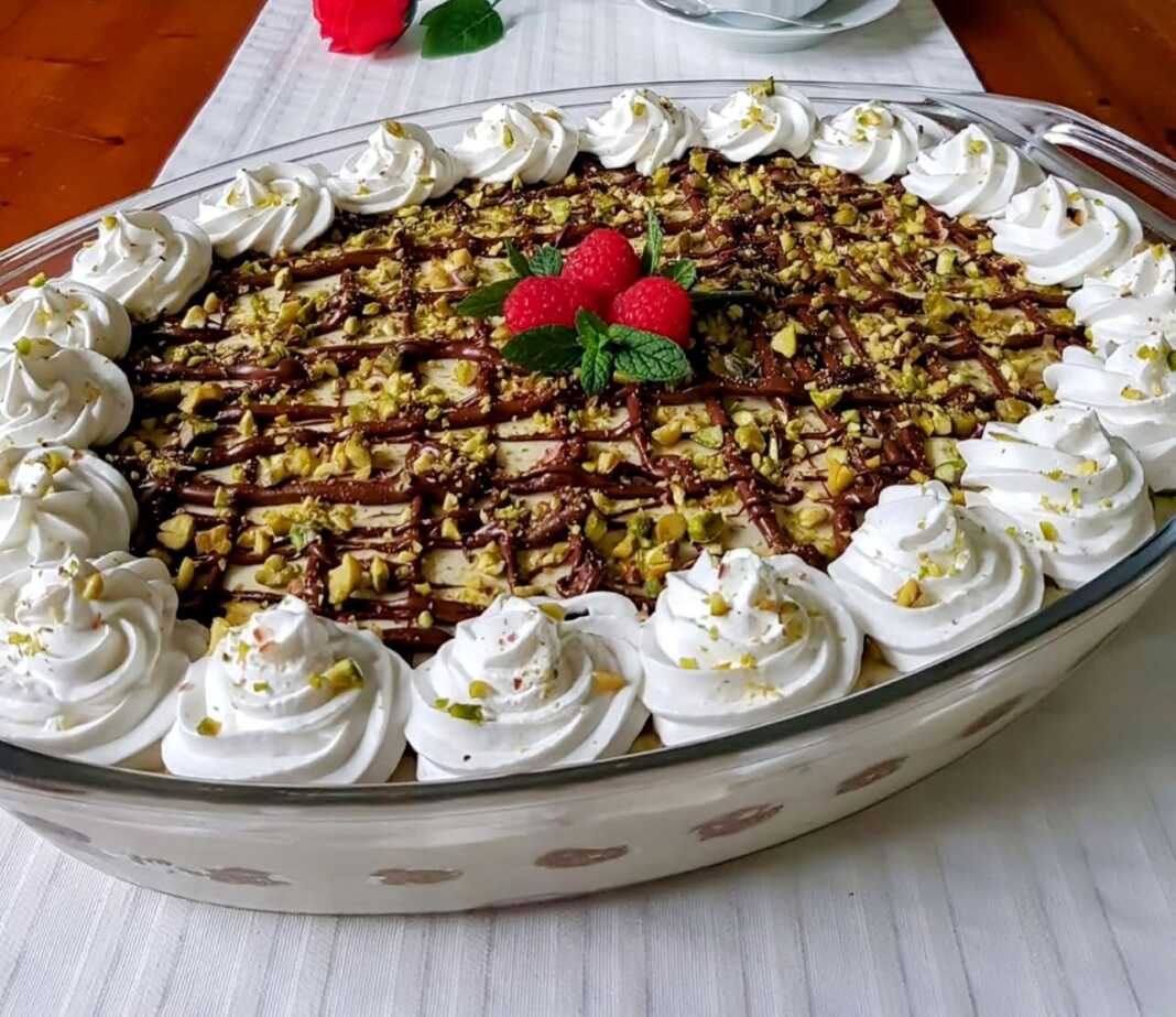 Ένα γυάλινο μπολ γεμάτο με στρώσεις από σαβαγιάρ, κρέμα φυστικιού, νουτέλα και γαρνιρισμένο με ψιλοκομμένα φυστίκια.