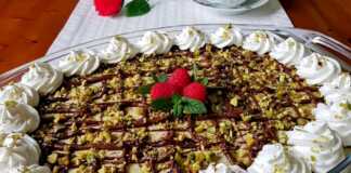 Ένα γυάλινο μπολ γεμάτο με στρώσεις από σαβαγιάρ, κρέμα φυστικιού, νουτέλα και γαρνιρισμένο με ψιλοκομμένα φυστίκια.