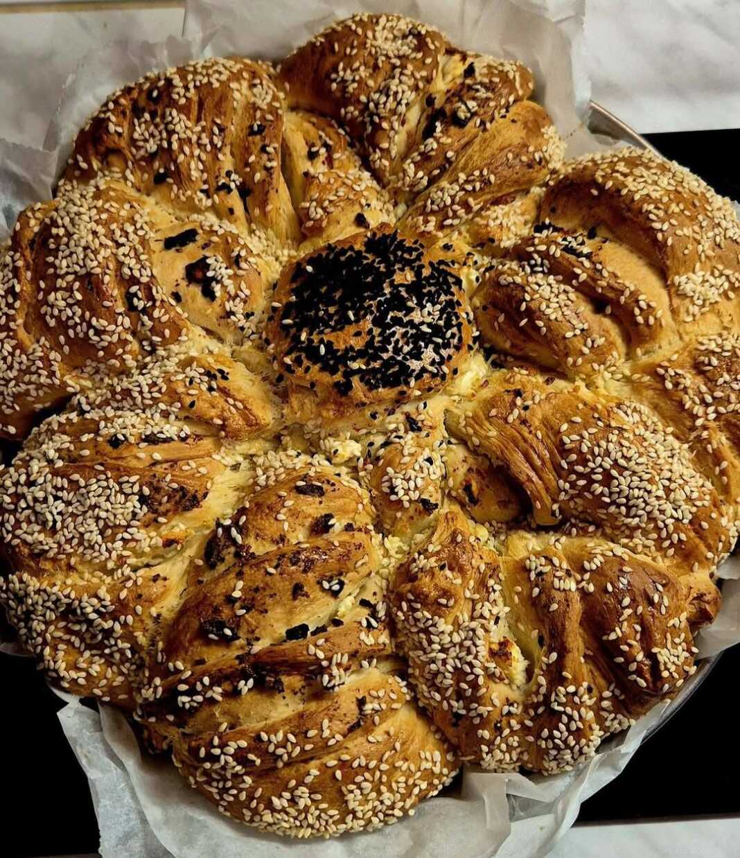 Μία όμορφη, πλεγμένη τυροκουλούρα με χρυσαφένια κρούστα, πασπαλισμένο με σουσάμι.