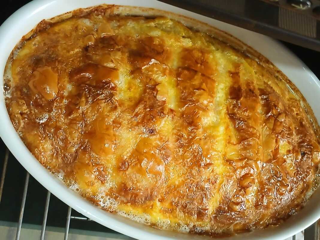 Φωτογραφία με μια χρυσαφένια, ψημένη τυρόπιτα σε ταψί.