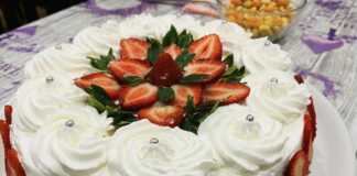 Μια ολόκληρη, όμορφα διακοσμημένη τούρτα φράουλα, με φρέσκες φράουλες και κρέμα, έτοιμη για σερβίρισμα.