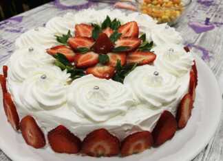 Μια ολόκληρη, όμορφα διακοσμημένη τούρτα φράουλα, με φρέσκες φράουλες και κρέμα, έτοιμη για σερβίρισμα.