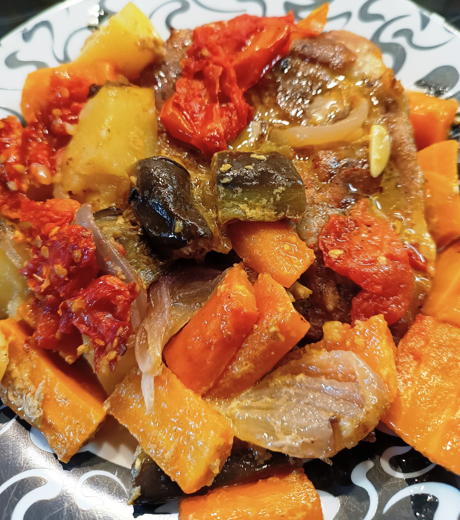 Χοιρινές μπριζόλες στην γάστρα με πατάτες, καρότα και μελιτζάνες, έτοιμες για σερβίρισμα.