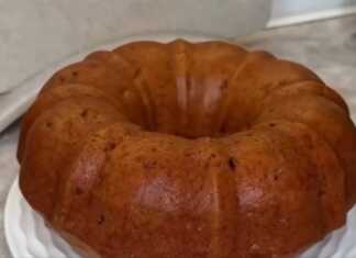 Ένα κέικ με σταφίδες και χοντροκομμένα καρύδια, πάνω σε μια πιατέλα, με ολόκληρο το κέικ στο φόντο.