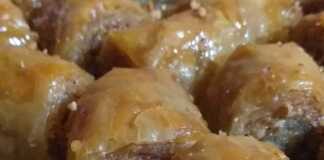 Μια πιατέλα γεμάτη με χρυσαφένια, σιροπιαστά μπακλαβαδάκια, πασπαλισμένα με τριμμένα φιστίκια.