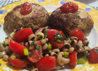 Δύο μπιφτέκια γεμιστά με τυρί σε ένα ταψί με λαδόκολλα, δίπλα σε ένα μπολ με σαλάτα από μαυρομάτικα φασόλια και κόκκινα ντοματίνια.