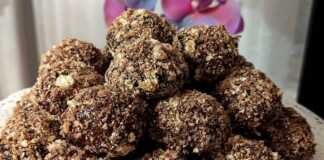 Μια πιατέλα γεμάτη μικρά, στρογγυλά μπισκότα καλυμμένα με σκούρο γλάσο σοκολάτας και τριμμένη ανοιχτόχρωμη γκοφρέτα.