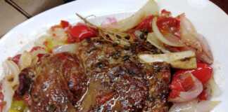 Μοσχαρίσια Μπριζόλα σε Λαδόκολλα με Λαχανικά Μια ψημένη μοσχαρίσια μπριζόλα σε ένα ανοιχτό πακέτο λαδόκολλας, περιτριγυρισμένη από μαγειρεμένα κομμάτια ντομάτας, κρεμμυδιού και πιπεριάς.